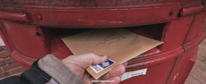 Main d'un homme mettant un courrier dans une boîte aux lettres anglaise.