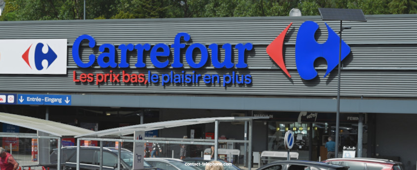 Vue extérieure d'un magasin Carrefour, le logo de l'enseigne y figure en grosses lettres.