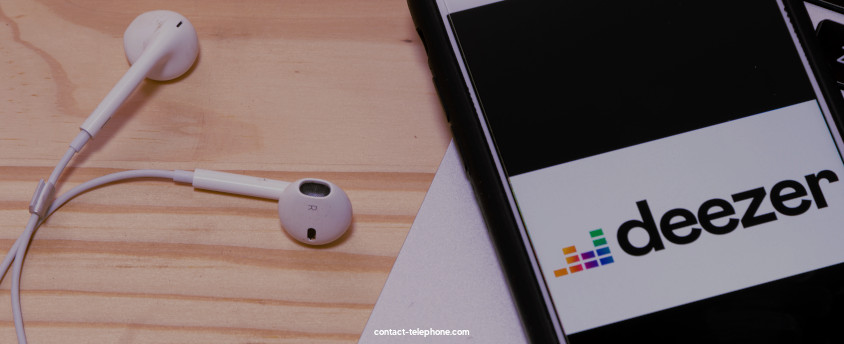 Écouteurs audios posés à côté d'un téléphone mobile affichant l'application Deezer.
