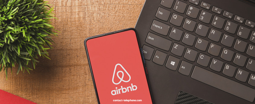 Clavier d'un ordinateur sur lequel est posé un téléphone connecté à l'application Airbnb.