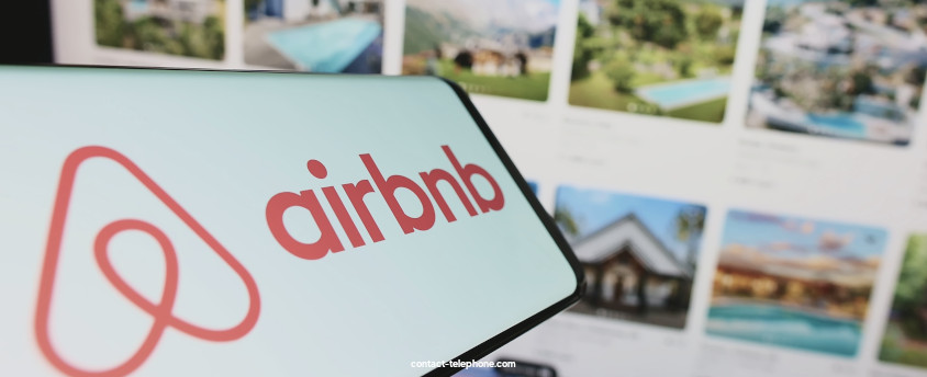 Téléphone portable indiquant le logo d'Airbnb placé devant un écran d'ordinateur connecté au site internet Airbnb.