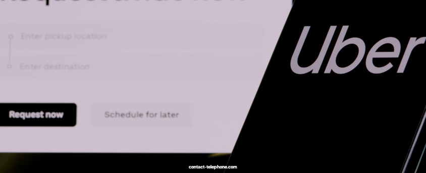 Téléphone portable affichant le logo Uber placé devant un écran d'ordinateur sur lequel une page du site Uber est ouverte.