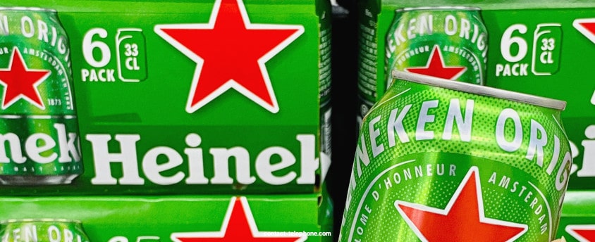 Une canette de bière Heineken devant des packs de la même marque de bières.