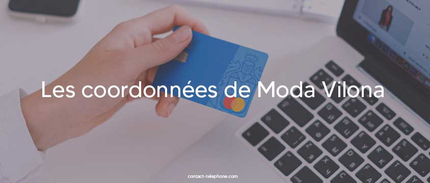 Main tenant une carte bancaire devant un ordinateur pour acheter des vêtements en ligne.